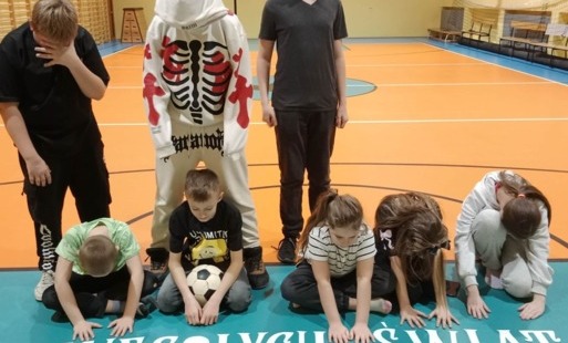 dzieci stoją na sali, na podłodze leży napis Wesołych Świat